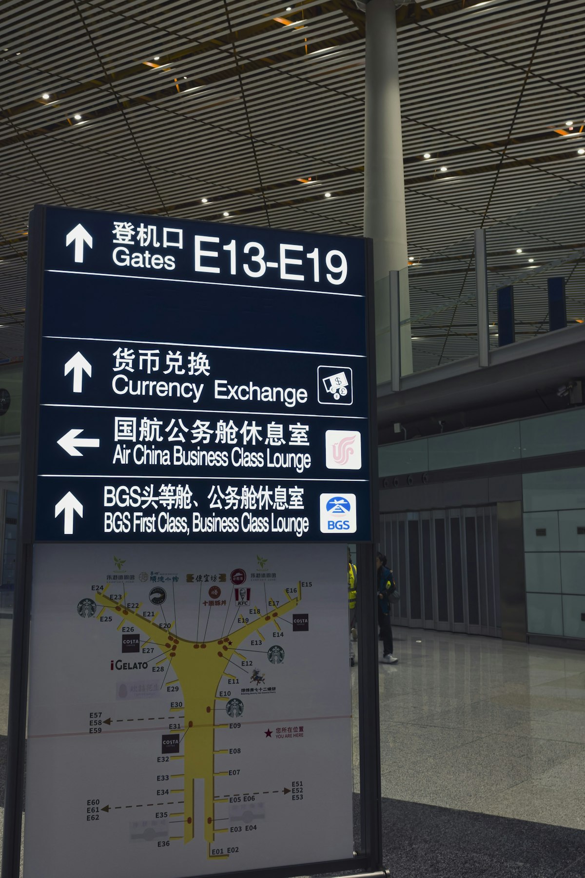 Airport terminal signs showing gates and currency exchange directions