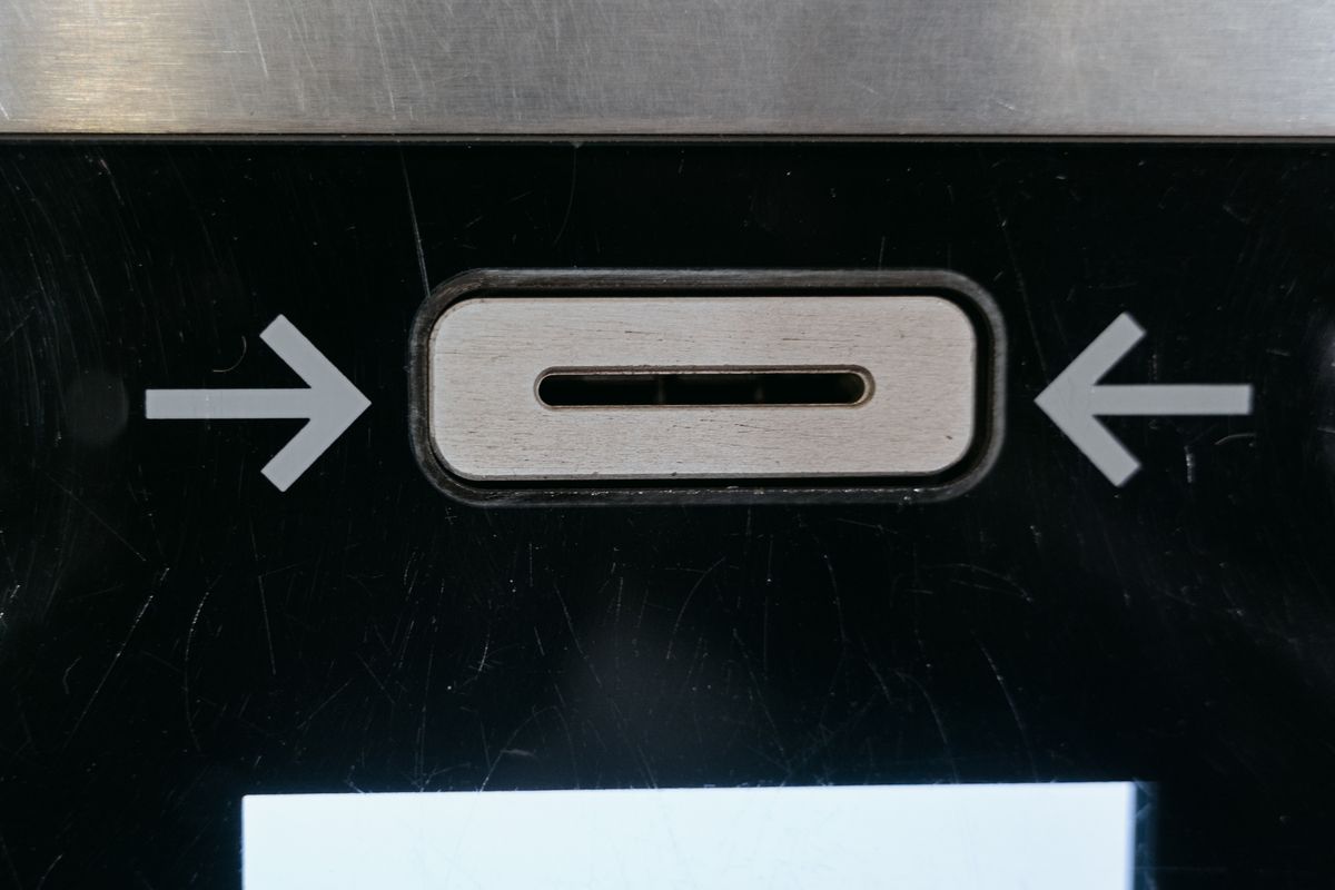 Close-up of an ATM card slot with arrows showing the card insertion direction