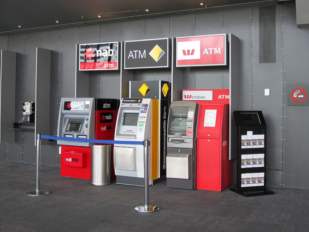 A row of bank ATMs from four different banks side by side against a grey wall